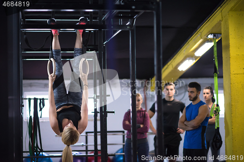 Image of woman working out with personal trainer on gymnastic rings