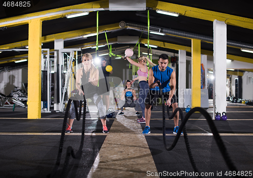 Image of sports couple doing battle ropes cross fitness exercise