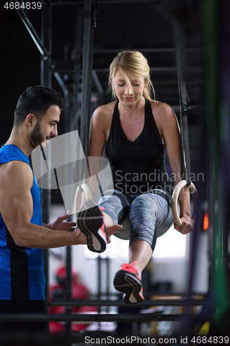 Image of woman working out with personal trainer on gymnastic rings