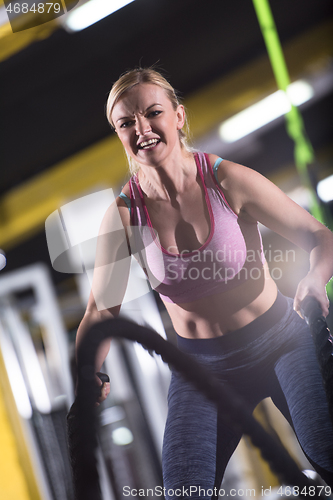 Image of athlete woman doing battle ropes cross fitness exercise