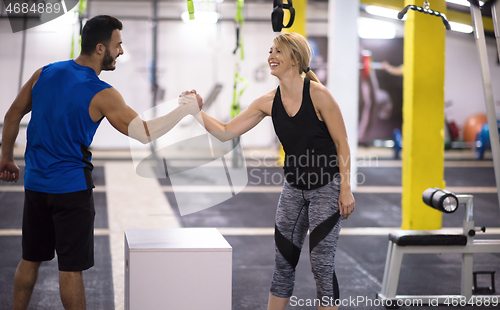 Image of woman working out with personal trainer jumping on fit box