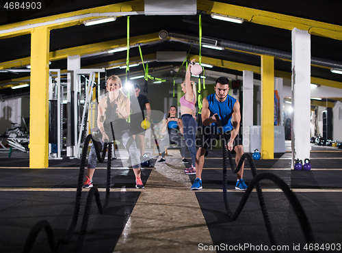 Image of sports couple doing battle ropes cross fitness exercise