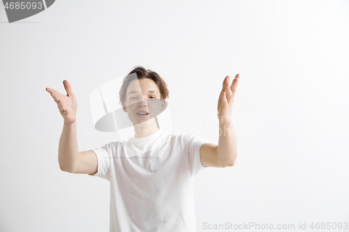 Image of The happy businessman standing and smiling against gray background.