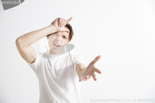Image of Losers go home. Portrait of happy guy showing loser sign over forehead