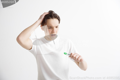 Image of Upset man looking in pregnancy test. Frustrated model