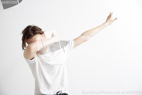 Image of Young man makes the dab movement with his arms on a gray background.