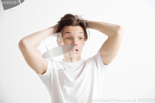 Image of The young attractive man looking suprised isolated on gray