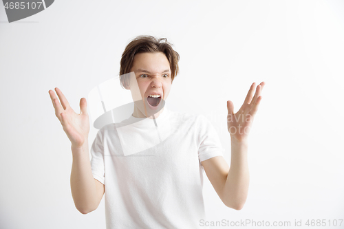 Image of The young attractive man looking suprised isolated on gray