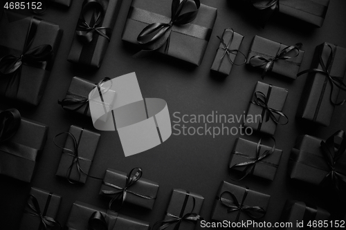 Image of Arranged Gifts boxes wrapped in black paper with black ribbon on black background. Christmas concept