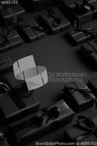 Image of Arranged Gifts boxes wrapped in black paper with black ribbon on black background. Christmas concept