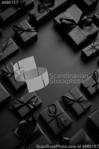 Image of Arranged Gifts boxes wrapped in black paper with black ribbon on black background. Christmas concept