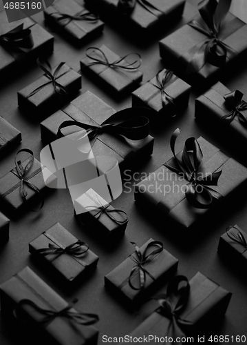 Image of Elegant black Christmas theme. Wrapped gifts in black matte paper with ribbon