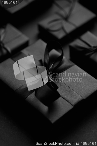 Image of Black Christmas concept. Close up on elegant black matte wrapped gifts with ribbon.