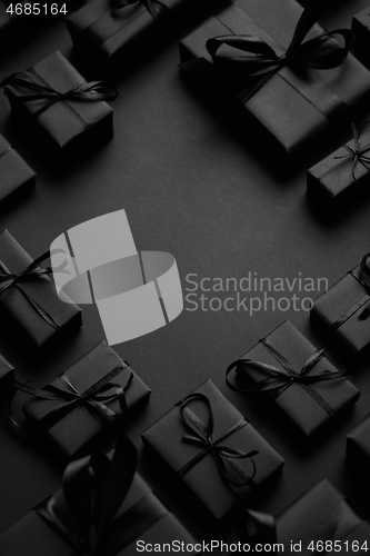 Image of Arranged Gifts boxes wrapped in black paper with black ribbon on black background. Christmas concept