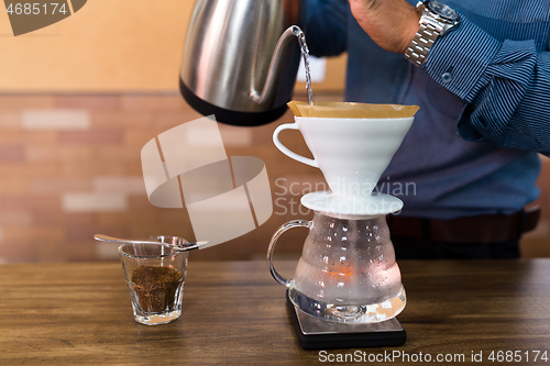 Image of Barista pouring water on coffee with filter