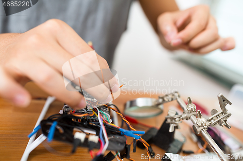 Image of Man connecting the wire of flying drone