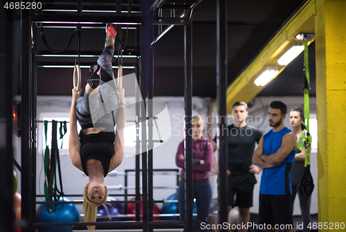 Image of woman working out with personal trainer on gymnastic rings