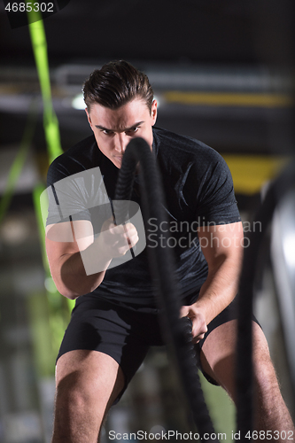 Image of athlete man doing battle ropes cross fitness exercise