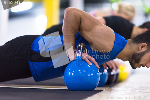 Image of young athletes doing pushups with kettlebells