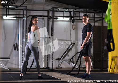 Image of sports couple doing battle ropes cross fitness exercise