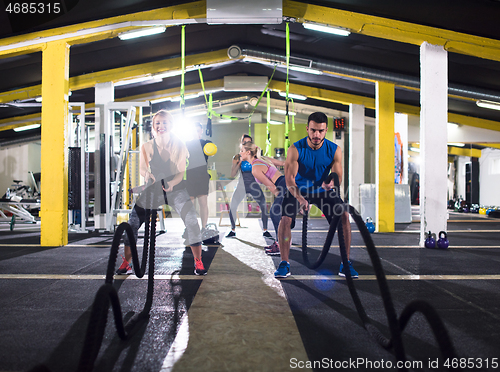 Image of sports couple doing battle ropes cross fitness exercise