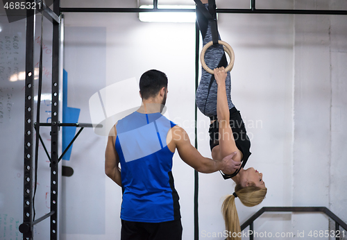 Image of woman working out with personal trainer on gymnastic rings