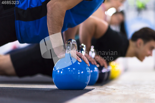 Image of young athletes doing pushups with kettlebells