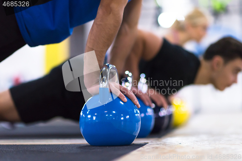 Image of young athletes doing pushups with kettlebells