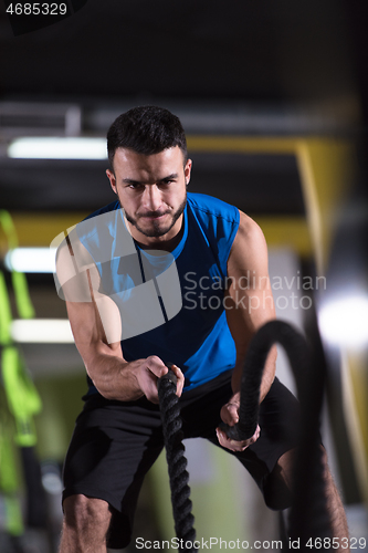 Image of athlete man doing battle ropes cross fitness exercise