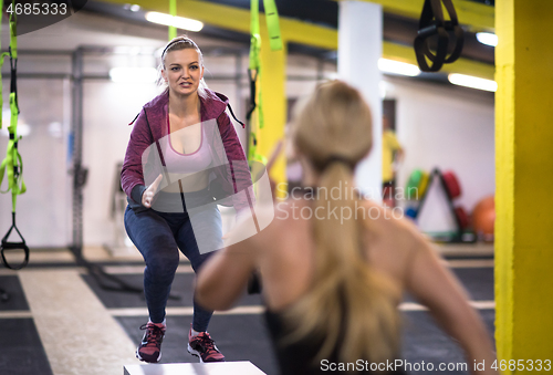 Image of athletes working out  jumping on fit box