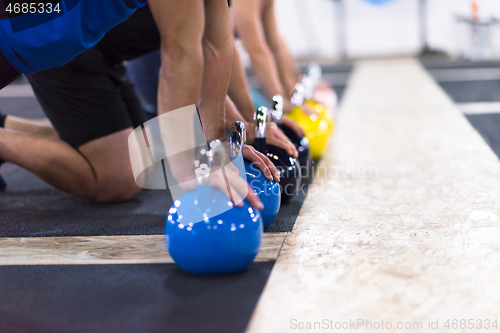 Image of young athletes doing pushups with kettlebells