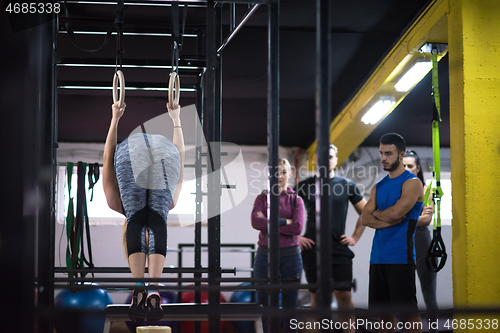 Image of woman working out with personal trainer on gymnastic rings