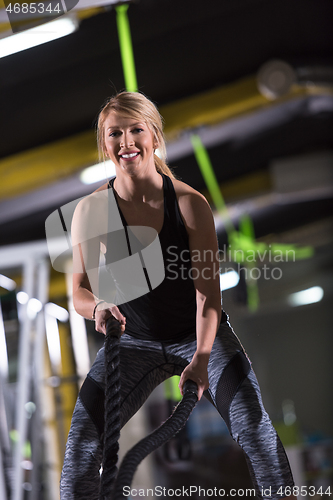 Image of athlete woman doing battle ropes cross fitness exercise