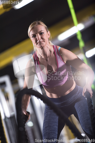 Image of athlete woman doing battle ropes cross fitness exercise