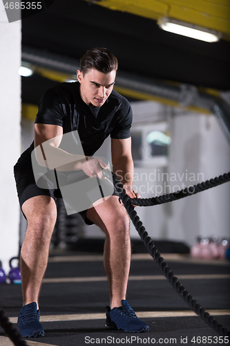 Image of athlete man doing battle ropes cross fitness exercise