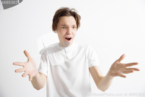 Image of The young attractive man looking suprised isolated on gray