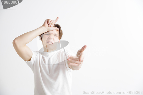 Image of Losers go home. Portrait of happy guy showing loser sign over forehead