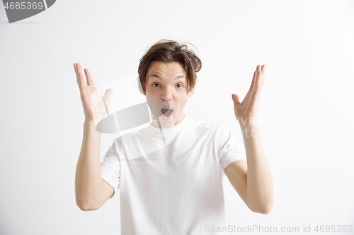 Image of The young attractive man looking suprised isolated on gray