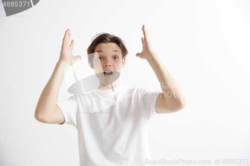 Image of The young attractive man looking suprised isolated on gray