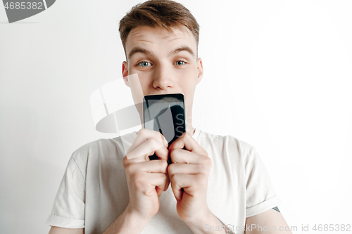 Image of Young handsome man showing smartphone screen and signing OK isolated on gray background