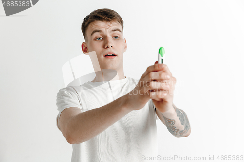 Image of Happy man looking at pregnancy test at studio