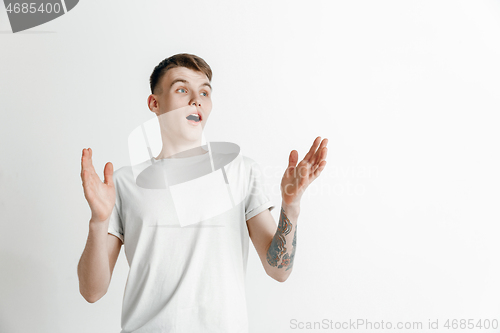 Image of The young attractive man looking suprised isolated on gray