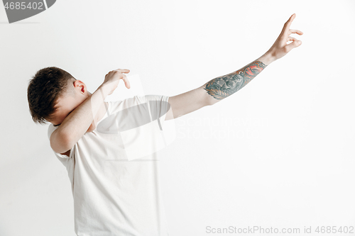 Image of Young man makes the dab movement with his arms on a gray background.