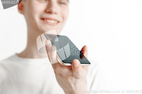 Image of Indoor portrait of attractive young man holding smartphone