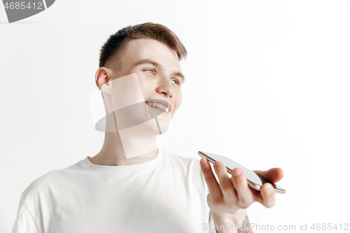 Image of Indoor portrait of attractive young man holding smartphone