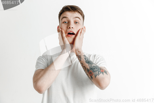 Image of The young attractive man looking suprised isolated on gray