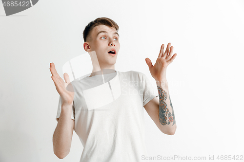 Image of The young attractive man looking suprised isolated on gray