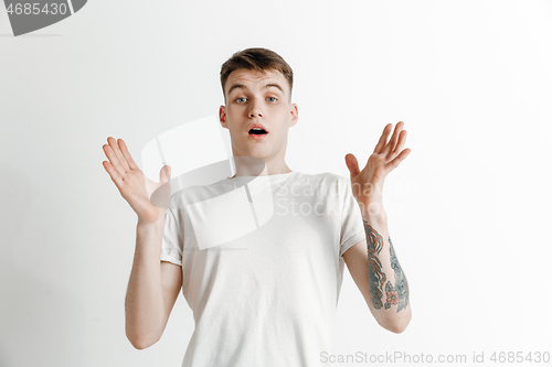 Image of The young attractive man looking suprised isolated on gray