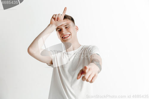 Image of Losers go home. Portrait of happy guy showing loser sign over forehead