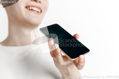 Image of Indoor portrait of attractive young man holding smartphone